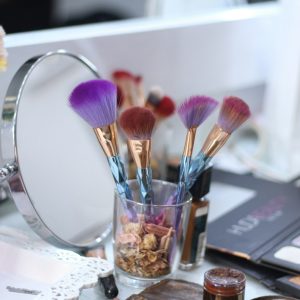 a close up of makeup brushes in a cup on a table